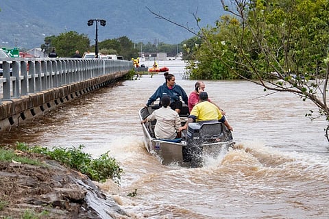 Residents cross floodwaters by boat in Cairns on December 18, 2023. (Photo | AFP)
