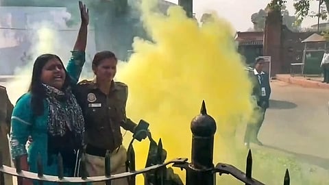 FILE: Police personnel detain a woman protesting outside the Parliament building carrying a can emitting a yellowish smoke during the Winter session, in New Delhi. (Photo | PTI)