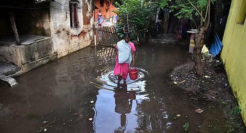 A woman walks in flooded water in front of her home to fetch water at Karukku Road Near Patravakkam Ambattur after recent rain lashed  Chennai. (Photo | P.Ravikumar, EPS)