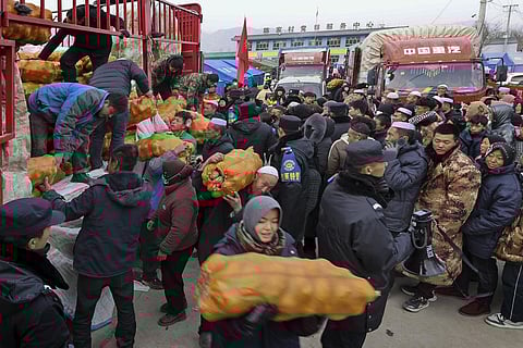 Volunteers distribute foods to quake victims at a temporary settlement in Chenjiacun village in Jishishan county in northwest China's Gansu province on Wednesday, Dec. 20, 2023. (Photo | AP)