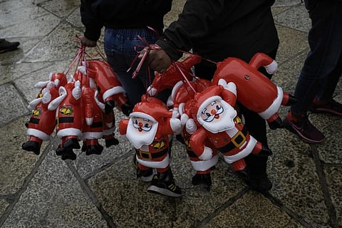 People hold Santa Claus balloons on Christmas Eve, near the Church of the Nativity, in the West Bank city of Bethlehem. (Photo | AP)