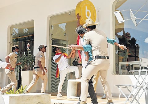 Police personnel stop KRV members from vandalising business establishments, demanding that they put up Kannada name boards and hoardings and minimise the use of English ones, in Bengaluru on Wednesday
