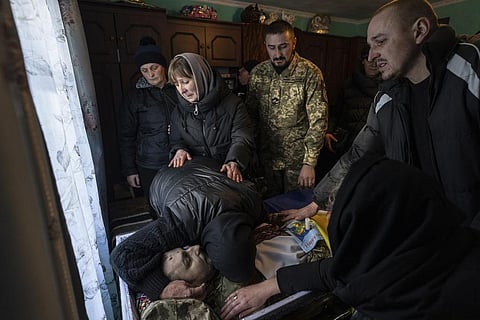The mother of Ukrainian army officer Vasyl Medviychuk hugs her son's body during a funeral inside a house in the Carpathian mountains in Krasnyk village, Ukraine, Friday, Dec. 29, 2023. | AP