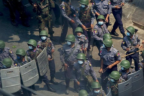 Police and soldiers armed with guns and slingshots advance towards anti-coup protesters in Mandalay, Myanmar. (Photo | AP)