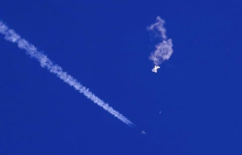The remnants of a large balloon drift above the Atlantic Ocean, just off the coast of South Carolina, with a fighter jet and its contrail seen below it, Feb. 4, 2023. (File Photo | AP)