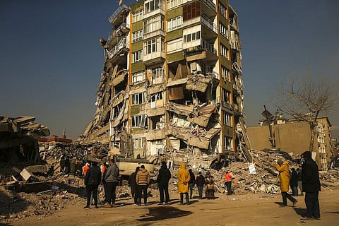 People stand by a collapsed building in Kahramanmaras, southern Turkey, Sunday, Feb. 12, 2023. (Photo | AP)