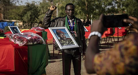 A man poses for a picture as he stands next to the coffin containing the remains of Burkina Faso's revolutionary leader, Thomas Sankara, during his reburial ceremony.(Photo | AP)