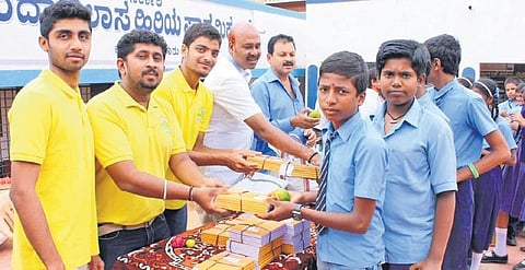 Members of the Spandhana Trust distribute notebooks to students  of government schools