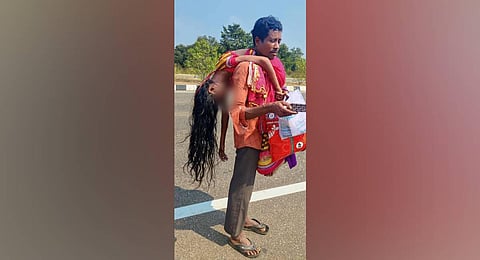 An Odiya man carries his wife's body on his shoulders after she died while travelling in an auto at Chelluru Ring Road, in Vizianagaram. (Photo | PTI)