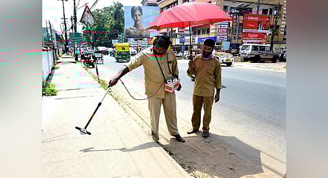 A KSEB worker holding an umbrella for a coworker in the scorching sun as they detect cables for maintenance work, in Kozhikode. (Photo | E Gokul, EPS)