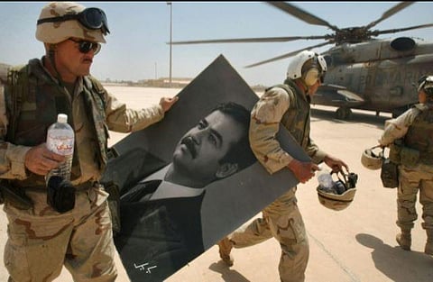 U.S. Marines carry a portrait of toppled Iraqi President Saddam Hussein at the international airport in Baghdad, in this file photo from April 14, 2003. (Photo | AFP)