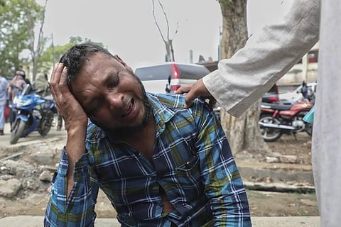 An unidentified man grieves as relatives receive bodies of victims of a road accident after a bus fell into a roadside ditch in Madaripur district, Bangladesh, March 19, 2023. (Photo | AP)