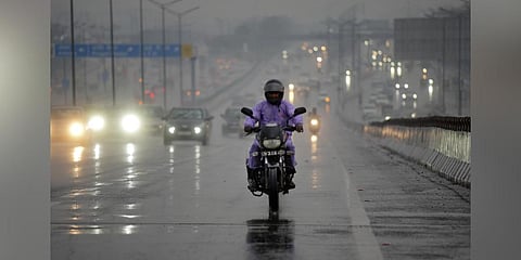 A man rides his bike on a road near Akshardham amid rainfall, in New Delhi, Saturday, March 18, 2023. (Photo | PTI)