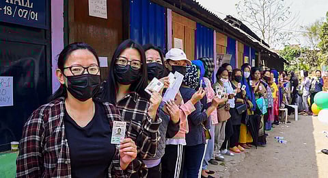 Voters standing in a queue show their ID cards before casting their votes for the Nagaland Assembly election, at a polling booth in Dimapur. 