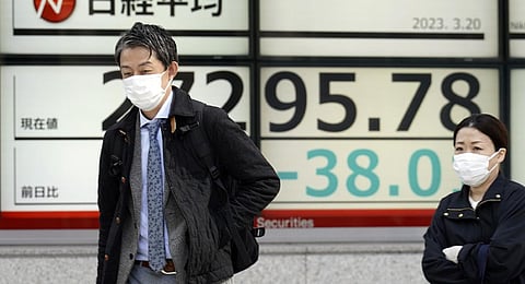 People walk in front of an electronic stock board showing Japan's Nikkei 225 index at a securities firm Monday, March 20, 2023, in Tokyo. (Photo | AP)