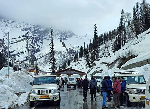 People walk on road after fresh snowfall at the South Portal of Atal Tunnel, at Rohtang near Manali, on March 19, 2023. (Photo | PTI)