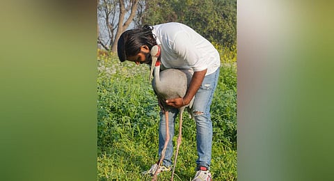 Arif Khan Gurjar with a 'Sarus' crane that has 'befriended' him, at Mandaka Village in Jamo block, in Amethi district, UP. (Photo | PTI)