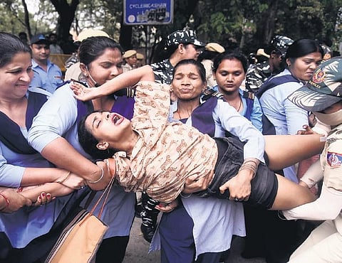 Police detain a protestor at Delhi University in New Delhi on Friday.  (Photo| PTI)