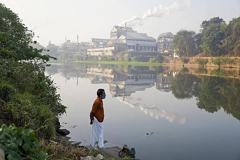 Adam Kutty stands on the bank of the Periyar River with smokestacks in the distance in Eloor, Kerala state, India, March 3, 2023. (Photo | AP)