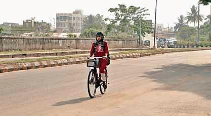 A woman cycles on a deserted road keeping her head covered with dupatta in Bhubaneswar. (Photo | Shamim Qureshy, Express)