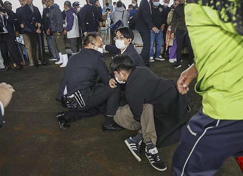 A man, on the ground, who threw what appeared to be a smoke bomb, is caught at a port in Wakayama, western Japan Saturday, April 15, 2023. (Photo | AP)