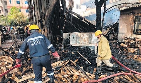 Firefighters along with police personnel douse the flames and rescue trapped persons after a fire broke out in a timber depot in Kushaiguda on Sunday