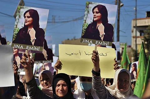 Women in Iran hold posters of Mahsa Amini condemning her death in the custody of the morality police who had detained her for not wearing a headscarf. (Photo | AP)