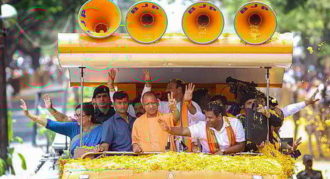 UP CM and senior BJP leader Yogi Adityanath flashes the victory sign during an election campaign roadshow ahead of upcoming Karnataka Assembly polls, in Mandya. (Photo | PTI)