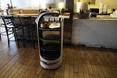 A BellaBot robot at the Noodle Topia restaurant delivers food and drinks to a table. (Photo | AP)