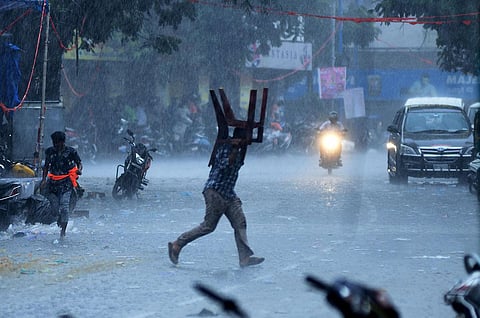 A man uses a plastic chair as cover to protect himself from the sudden spell of rainfall in Hyderabad. (Photo | Vinay Madapu, EPS)