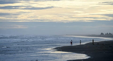 People stand by the sea in Sittwe in Myanmar’s Rakhine state ahead of the expected arrival of Cyclone Mocha. (Photo | AFP)