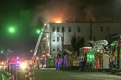 In this image made from video, firetrucks stage outside a hostel in central Wellington, New Zealand, early Tuesday, May 16, 2023. (NewsHub via AP)