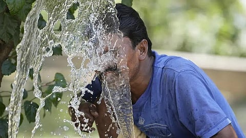 FILE - A person sprays water on his face from an irrigation pipe to beat the intense heat wave in Lucknow in Uttar Pradesh