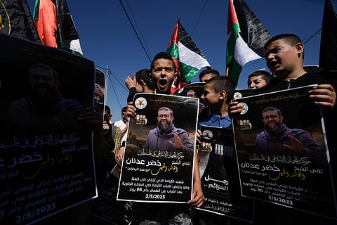 Palestinian kids wave their national flag and hold posters showing Khader Adnan. ( Photo | AP )