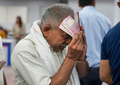 A man holds Rs 2000 currency notes at a bank in New Delhi, Tuesday, May 23, 2023.