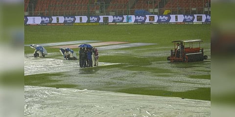 Groundsmen holding umbrellas near the covered pitch as it rains ahead of the IPL 2023 final cricket match between Gujarat Titans and Chennai Super Kings. (Photo | PTI)