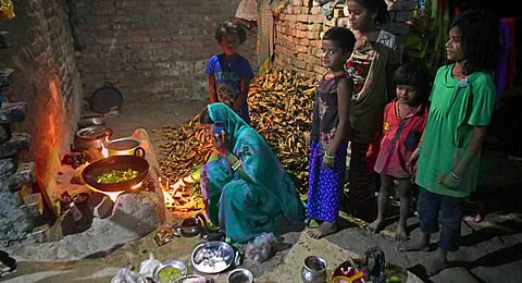 Jaimala Devi, mother-of-seven, cooks food as her children watch inside their village house in Darbhanga district of India's Bihar state.(Photo | AFP)