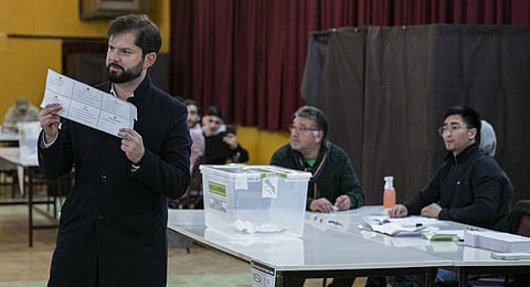 Chile's President Gabriel Boric shows his ballot prior to casting his vote during an election to choose members of a Constitutional Council.(Photo |AP)
