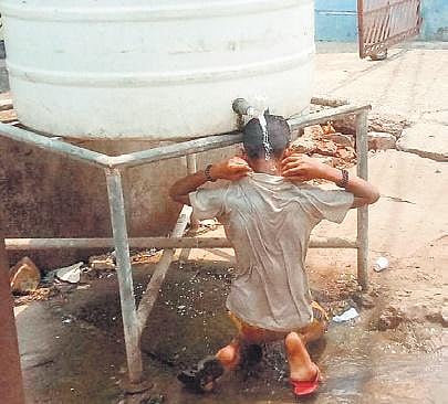 A boy bathing under a roadside water tank to beat the heat in Cuttack | Express