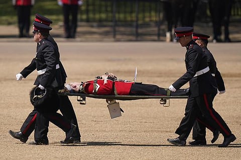 A trombone player of the military band is carried out on a stretcher after a faint during the Colonel's Review. ( Photo | AP)