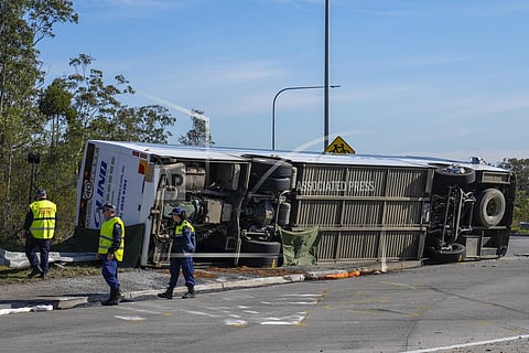 Police inspect underneath a bus that rolled onto its side near Greta in the Hunter Valley, north of Sydney, Australia, Monday, June 12. (Photo | AP)