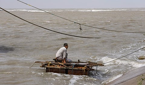 A worker fixes a cargo ship with ropes at the sea shore ahead of the landfall of Biparjoy cyclone, at Mandvi, in Kutch district, on June 14, 2023. (Photo | PTI)
