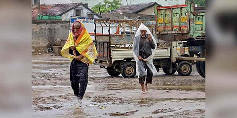 Villagers use plastic sheet to shield themselves during rainfall ahead of the landfall of Cyclone Biparjoy, in Kutch district, Thursday, June 15, 2023. (Photo | PTI)