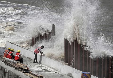 'Construction workers sitting at Marine Drive in Mumbai as high tidal waves lash the shore ahead of the landfall of Cyclone Biparjoy (Photo | PTI)