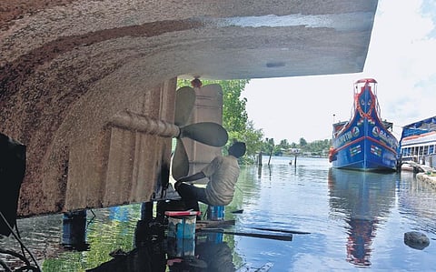 A mechanic works on the rudder of a boat in Vypeen