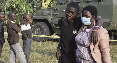 A boy is conforted at the scene of an attack in Mpondwe, Uganda. (Photo | AFP)