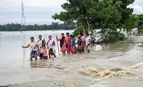 Villagers wade through the flood water at Dhamdama in Nalbari district of Assam on Wednesday. (Photo | ANI)