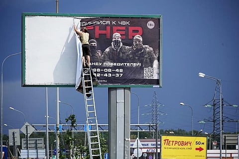 A man takes down the poster with writing reading 'Join us at Wagner', which is associated with the owner of the Wagner private military contractor, Yevgeny Prigozhin. (Photo | AP)