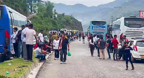 Commuters wait for the clearing of blocked Chandigarh-Manali highway following a landslide triggered by floods in Himachal Pradesh, in Mandi district, Monday, Jun 26, 2023. (PTI Photo)