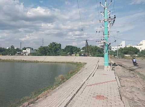Electric poles and transformer located around the pathway of a pond in Ariyalur | Express